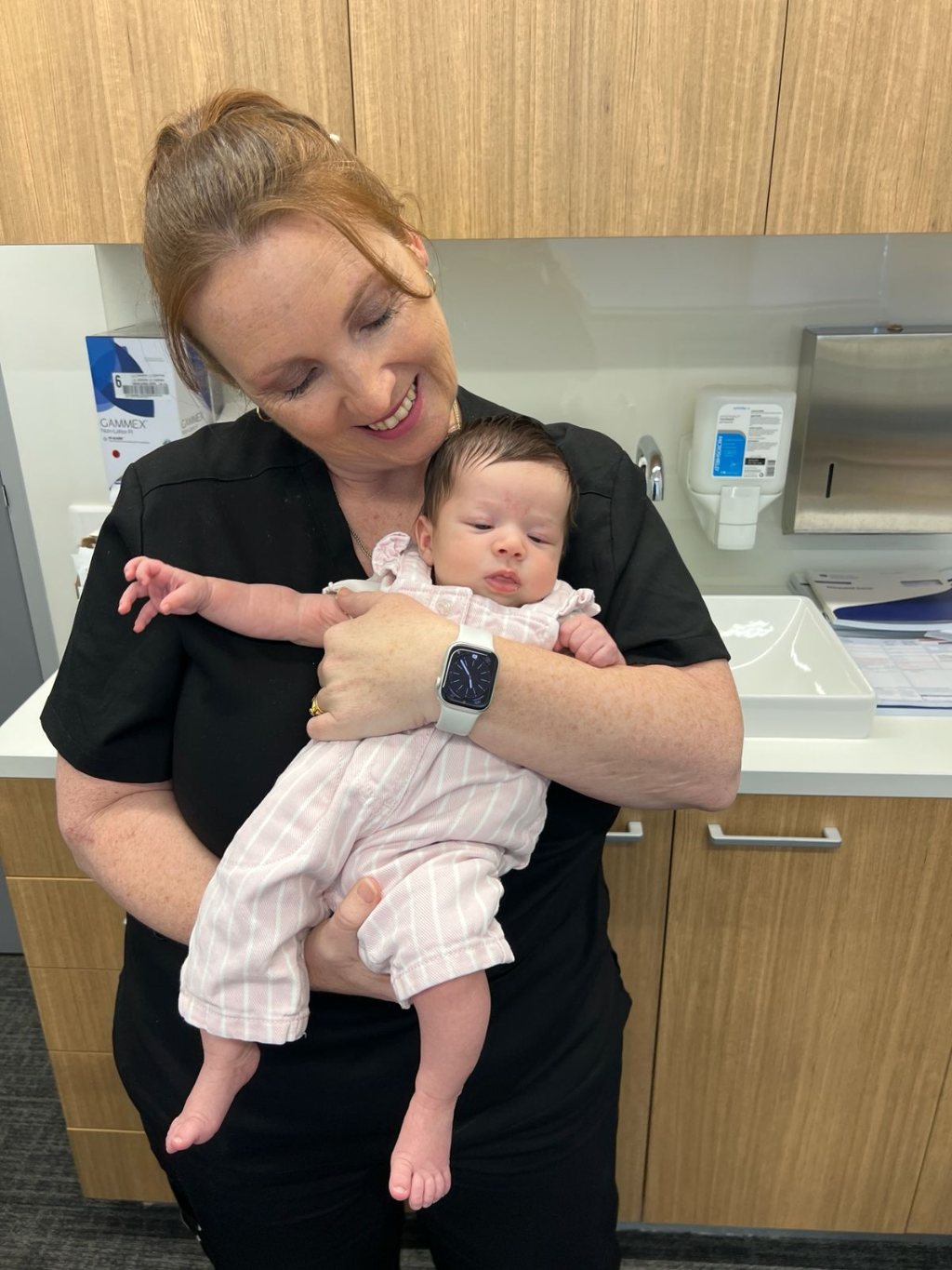Rebecca cradling a newborn baby and smiling down at them